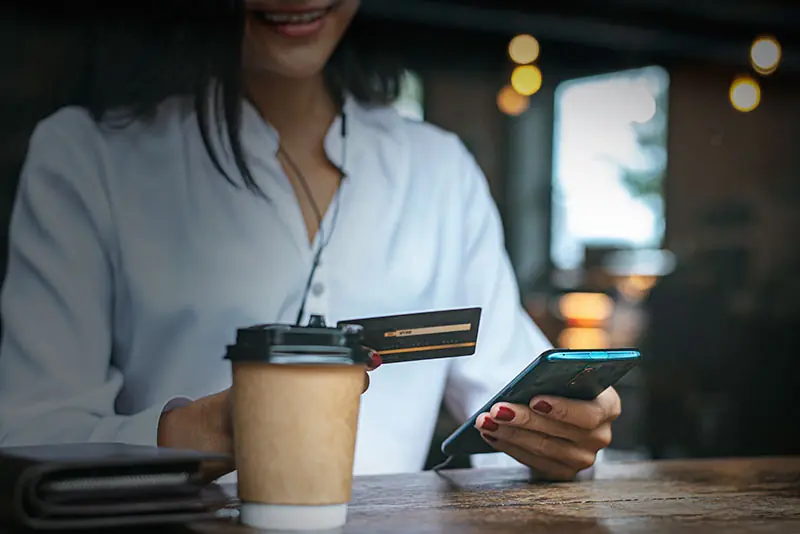 Mujer pagando una compra online con tarjeta de crédito desde su celular
